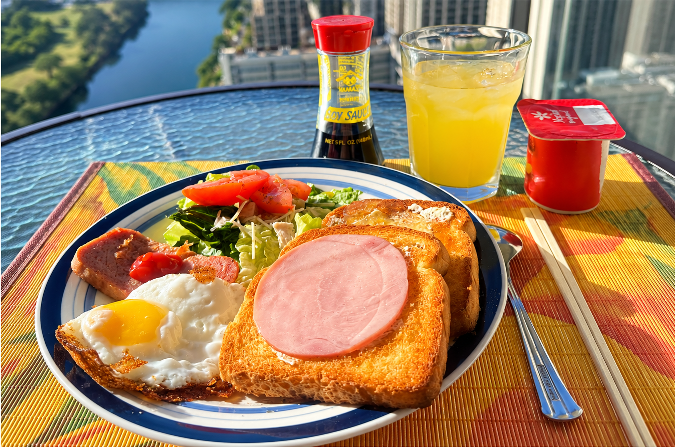 ハワイ・ワイキキのコンドミニアムで自炊した朝食。トースト、目玉焼き、サラダなどをラナイで楽しむ様子